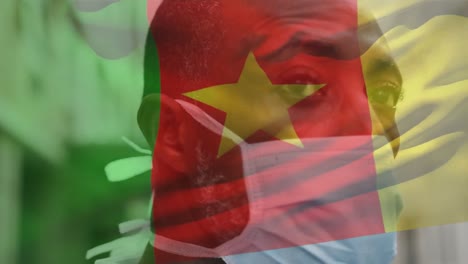 Animation-Der-Flagge-Kameruns,-Die-über-Einem-Afroamerikanischen-Mann-Mit-Gesichtsmaske-In-Der-Stadtstraße-Winkt