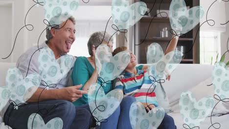 Animation-of-heart-balloons-over-happy-caucasian-grandparents-and-grandson-taking-selfie-at-home