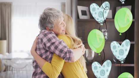 Animation-of-balloons-over-happy-caucasian-mother-and-her-adult-daughter-hugging-at-home