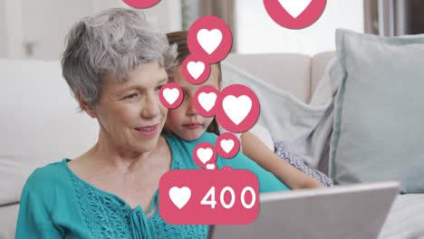 Animation-of-heart-icons-and-number-over-caucasian-grandmother-and-grandson-using-tablet