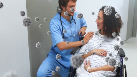Animation-of-coronavirus-cells-over-male-doctor-with-pregnant-patient-in-wheelchair