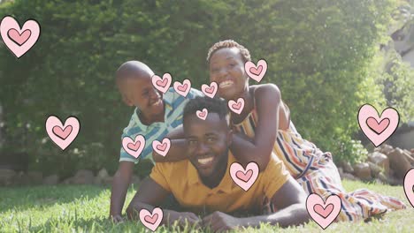 Animation-of-hearts-over-happy-african-american-family-in-garden