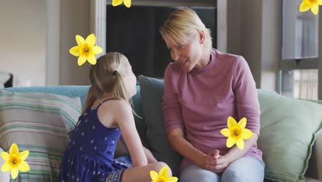 Animation-of-flowers-over-caucasian-mother-and-daughter-talking-and-smiling-on-sofa