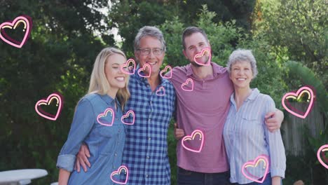 Animation-of-hearts-over-happy-caucasian-family-in-garden