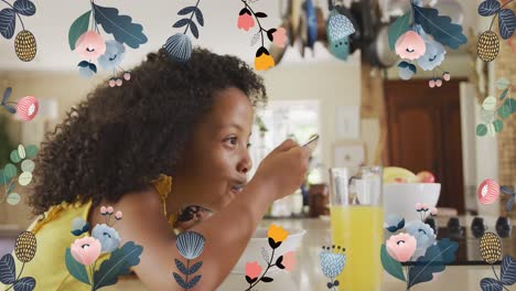 Animation-Von-Blumen-über-Einem-Afroamerikanischen-Mädchen,-Das-Zu-Hause-Frühstückt