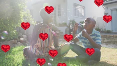 Animation-Von-Herzballons-über-Einer-Glücklichen-Afroamerikanischen-Mutter-Und-Ihrem-Sohn,-Die-Seifenblasen-Machen