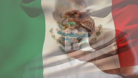 Animation-of-flag-of-mexico-waving-over-doctor-wearing-face-mask-and-holding-vaccine