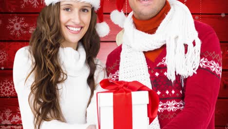 Animation-of-happy-caucasian-couple-keeping-present-wearing-santa-hats-over-red-background