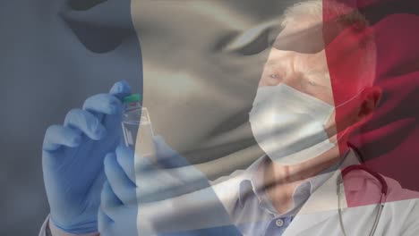 Animation-Der-Flagge-Frankreichs,-Die-über-Einem-Arzt-Winkt,-Der-Eine-Gesichtsmaske-Trägt-Und-Einen-Impfstoff-In-Der-Hand-Hält