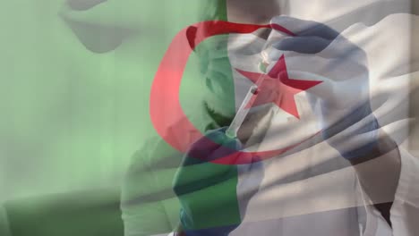 Animation-Der-Flagge-Algeriens,-Die-über-Einem-Arzt-Weht,-Der-Eine-Gesichtsmaske-Trägt-Und-Einen-Impfstoff-In-Der-Hand-Hält