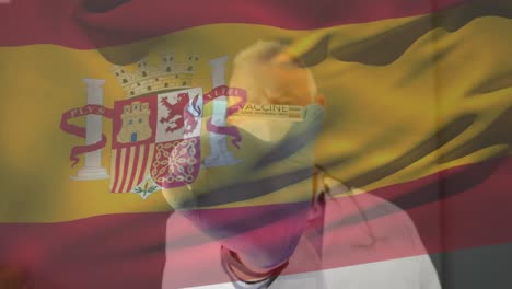 Animation-Der-Flagge-Spaniens,-Die-über-Einem-Arzt-Weht,-Der-Eine-Gesichtsmaske-Trägt-Und-Einen-Impfstoff-In-Der-Hand-Hält