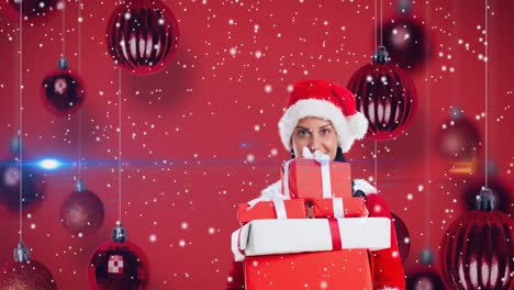 Animation-of-happy-caucasian-woman-wearing-santa-hat-keeping-presents-over-red-christmas-baubles