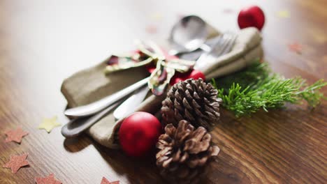 Video-of-christmas-decorations-with-bauble-and-pine-cones-and-cutlery-on-wooden-background