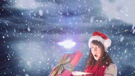 Animation-of-snow-falling-over-surprised-caucasian-woman-wearing-santa-hat-keeping-present