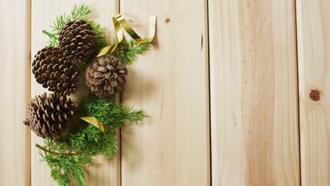 Video-of-christmas-decorations-with-pine-cones-and-copy-space-on-wooden-background
