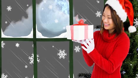 Animation-of-happy-asian-woman-keeping-present-over-window-and-christmas-tree