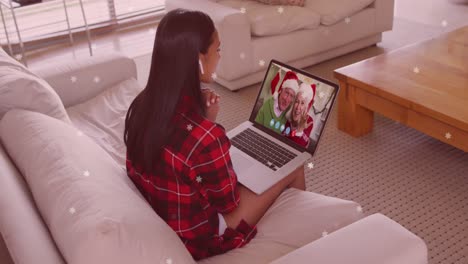 Animation-Von-Schnee,-Der-über-Eine-Glückliche-Kaukasische-Frau-Auf-Einem-Laptop-Videoanruf-Mit-Ihrer-Familie-Fällt