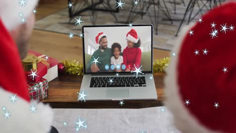 Animation-of-snow-falling-over-smiling-african-american-couple-in-santa-hats-on-laptop-video-call