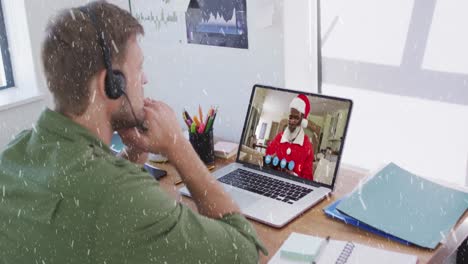 Animation-of-snow-falling-over-caucasian-man-with-headset-on-laptop-video-call-with-family