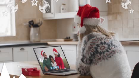 Animation-of-christmas-decorations-over-happy-caucasian-woman-in-santa-hat-on-laptop-video-call