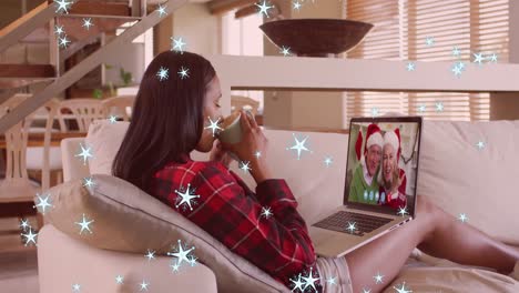 Animation-of-snow-falling-over-caucasian-woman-on-laptop-video-call-with-her-family