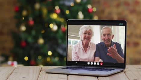 Kaukasisches-älteres-Paar-Winkt-Bei-Videoanruf-Auf-Laptop,-Mit-Weihnachtsbaum