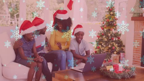 Animation-of-snow-falling-over-smiling-family-with-santa-hats-using-laptop