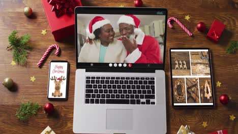Pareja-De-Ancianos-Afroamericanos-En-Videollamada-En-Una-Laptop,-Con-Smartphone,-Tablet-Y-Decoraciones