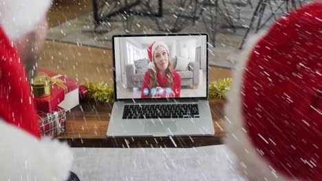 Animation-of-snow-falling-over-smiling-couple-in-santa-hats-on-laptop-video-call-with-family