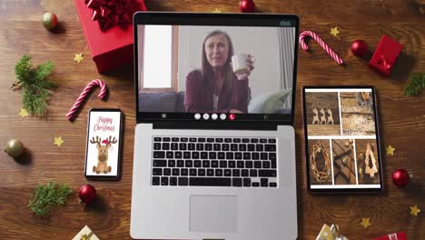 Happy-caucasian-senior-woman-on-video-call-on-laptop,-with-smartphone,-tablet-and-decorations
