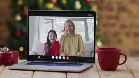 Happy-mother-and-daughter-on-video-call-on-laptop,-with-christmas-decorations-and-tree