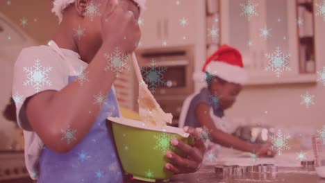 Animation-Von-Schnee,-Der-über-Zwei-Lächelnde-Kinder-Mit-Weihnachtsmützen-Fällt-Und-Kekse-Zubereitet