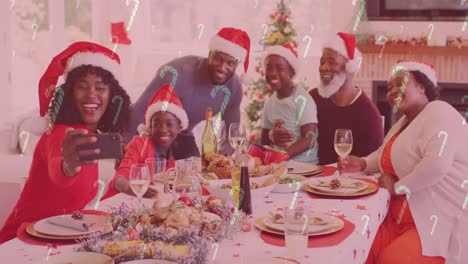 Animation-Von-Zuckerstangen,-Die-über-Eine-Lächelnde-Familie-Mit-Weihnachtsmützen-Fallen-Und-Ein-Selfie-Machen