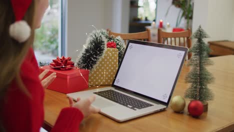 Kaukasische-Frau-Mit-Weihnachtsmütze-Führt-Videoanrufe-Zu-Hause-Auf-Dem-Laptop-Mit-Platz-Für-Kopien-Auf-Dem-Bildschirm