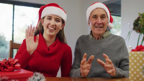 Glücklicher-Kaukasischer-älterer-Vater-Und-Erwachsene-Tochter-Mit-Weihnachtsmützen,-Die-Zu-Hause-Videoanrufe-Tätigen