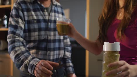 Smiling-senior-caucasian-father-and-teenage-daughter-preparing-health-drink-in-kitchen