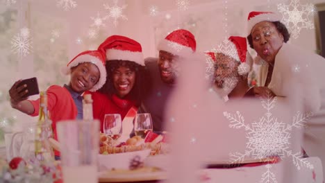 Animation-of-snow-falling-over-smiling-family-with-santa-hats-taking-selfie