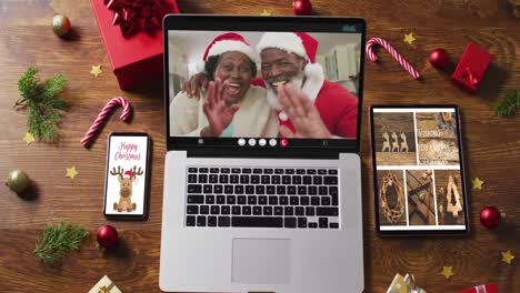 Pareja-De-Ancianos-Afroamericanos-En-Videollamada-En-Una-Laptop,-Con-Smartphone,-Tablet-Y-Decoraciones