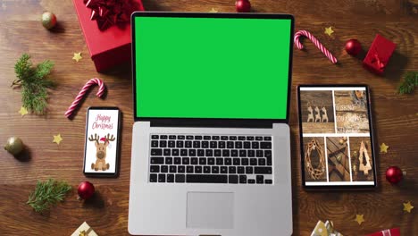Laptop-with-green-screen-on-screen,-with-smartphone,tablet-and-christmas-decorations
