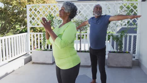 Animación-De-Una-Relajada-Pareja-De-Ancianos-Afroamericanos-Practicando-Yoga-En-El-Patio.