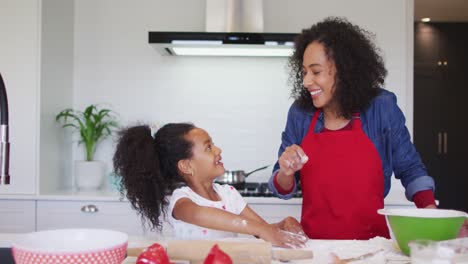 Happy-african-american-mother-and-daughter-using-tablet-and-baking-together