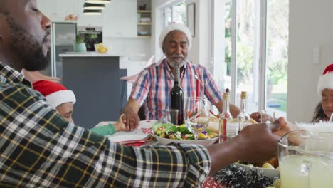 Feliz-Familia-Multigeneración-Afroamericana-Con-Gorros-De-Papá-Noel-Y-Celebrando-En-La-Cocina
