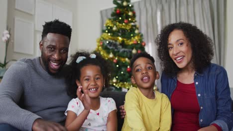 Familia-Afroamericana-Sonriente-Teniendo-Videollamadas-Y-Haciendo-Gestos,-Decoraciones-Navideñas-En-Segundo-Plano