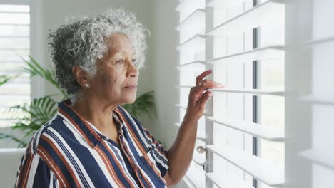 Ernsthafte-Afroamerikanische-ältere-Frau,-Die-Aus-Dem-Fenster-Schaut