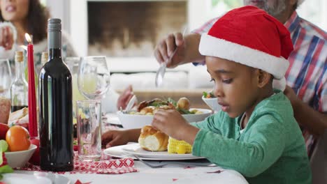 Glückliche-Afroamerikanische-Mehrgenerationenfamilie,-Die-Weihnachtsmützen-Trägt-Und-Das-Essen-Feiert