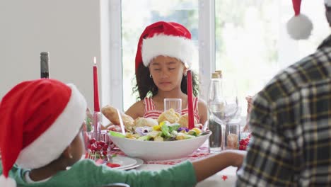 Glückliche-Afroamerikanische-Mehrgenerationenfamilie,-Die-Weihnachtsmützen-Trägt-Und-In-Der-Küche-Feiert