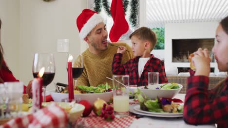 Caucasian-son-giving-his-father-food-with-fork-during-christmas-meal