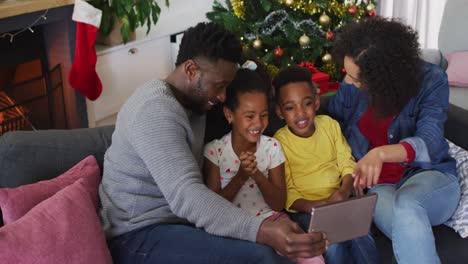 Smiling-african-american-family-having-video-call-and-gesturing,-christmas-decorations-in-background