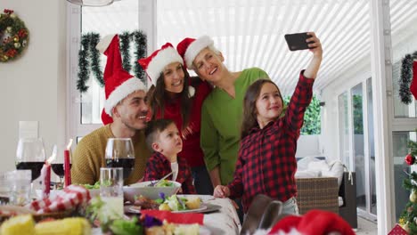 Glückliche-Kaukasische-Mehrgenerationenfamilie-Mit-Weihnachtsmützen,-Die-Ein-Selfie-Macht