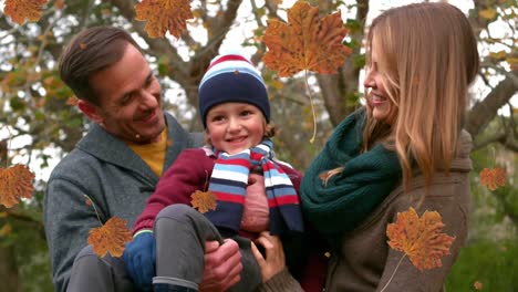 Animation-of-orangeautumn-leaves-falling-over-happy-caucasian-family-in-park